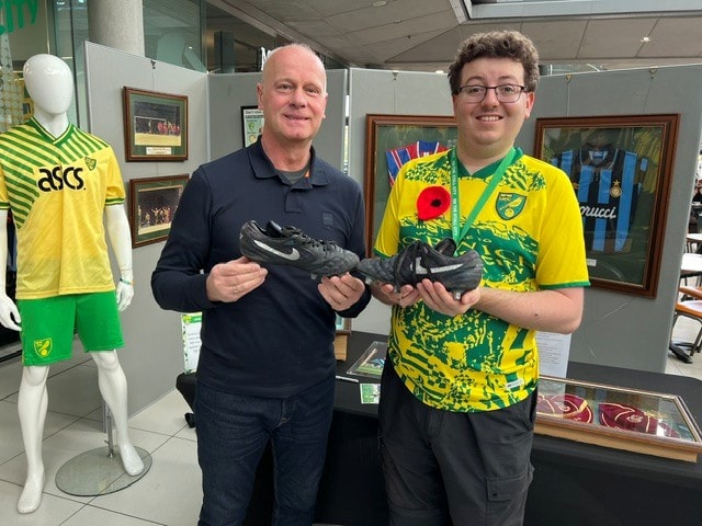 Two visitors holding match-worn boots at the November 2024 Poppy Event, The Forum Norwich